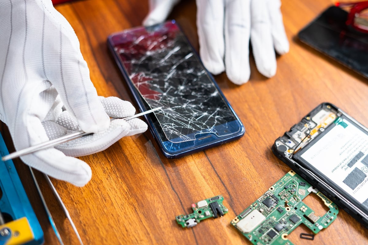 Technician fixing broken mobile phone display at workshop