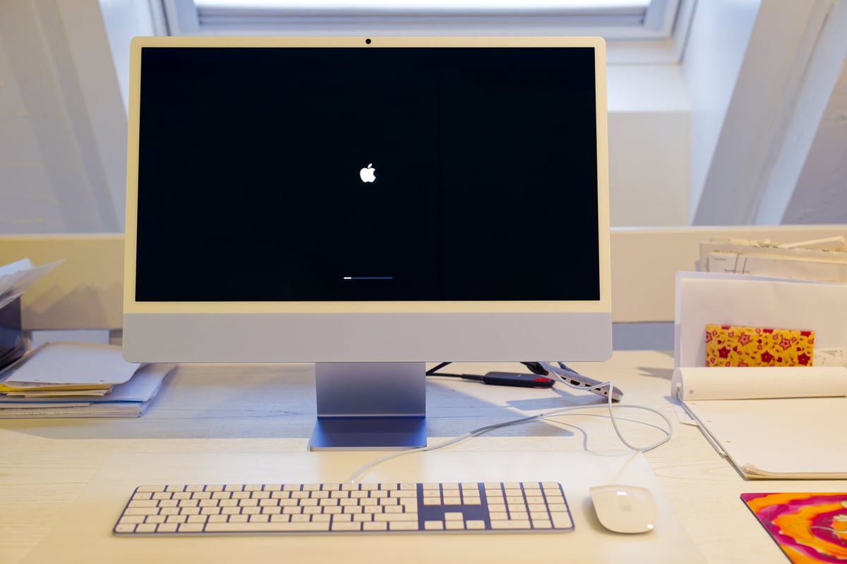 Close-up of brand new blue iMac M4 with start up screen on white desktop