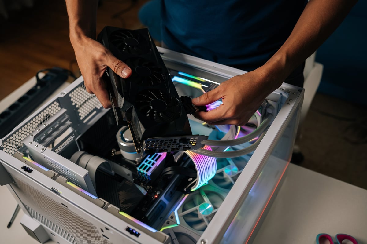 Computer professional inserting graphics card into custom gaming PC