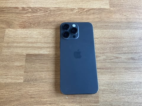 Blue iPhone 13 Pro displayed on wooden surface showing triple camera system on back