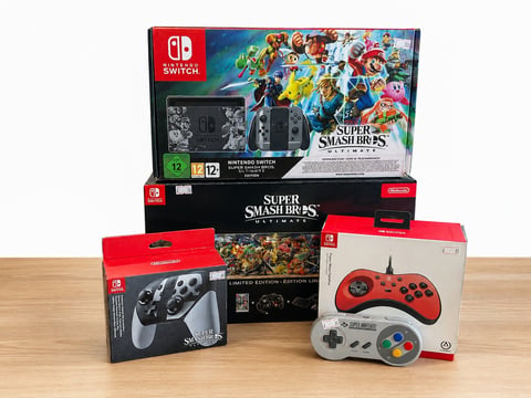 Nintendo Switch Super Smash Bros Ultimate bundle with console, controllers, and game accessories displayed on wooden surface