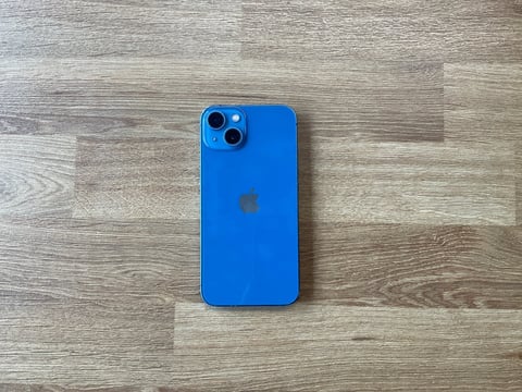 Blue iPhone with triple camera system on wooden surface